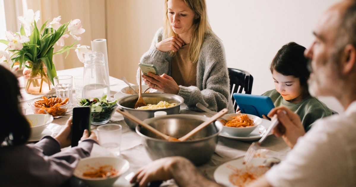 Család közös evés közben telefonjaikat nyomogatják