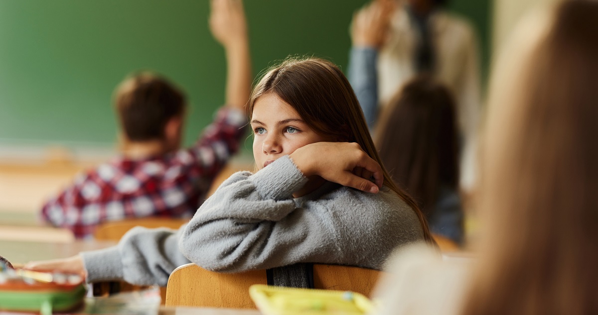 Fáradt gyerek ül az iskolapadban