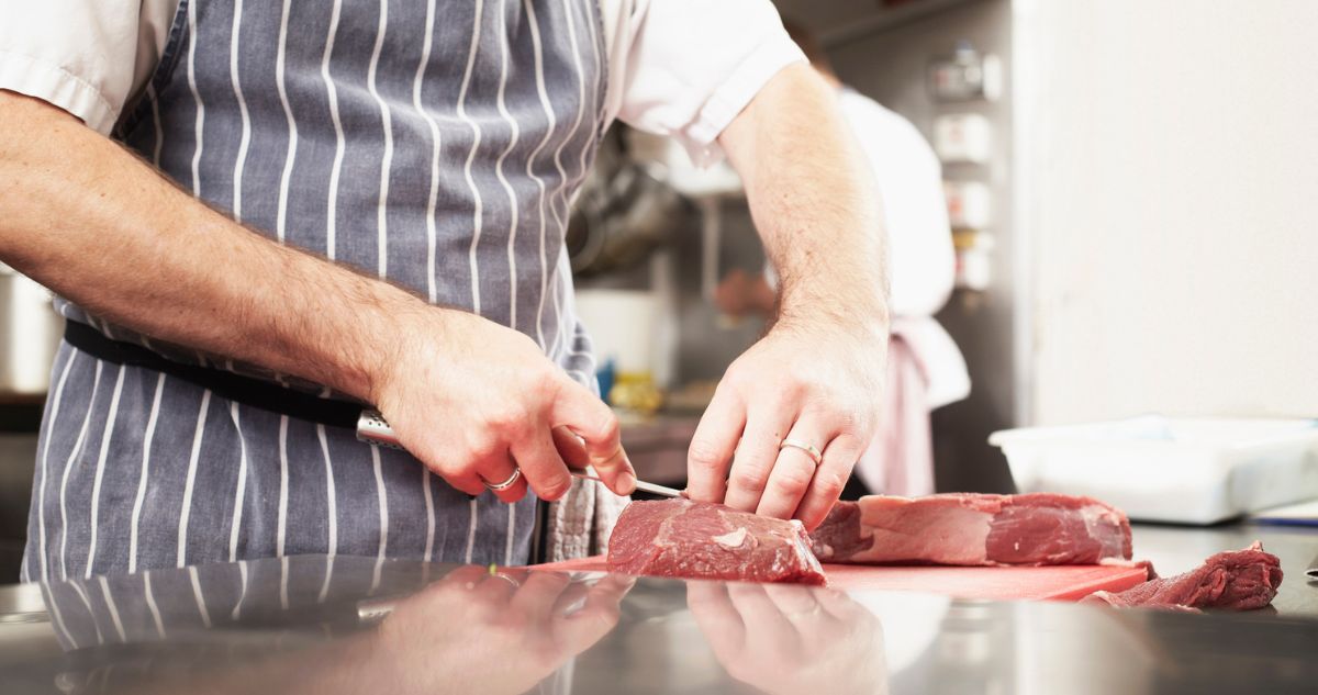 férfi kötényben húst szeletel