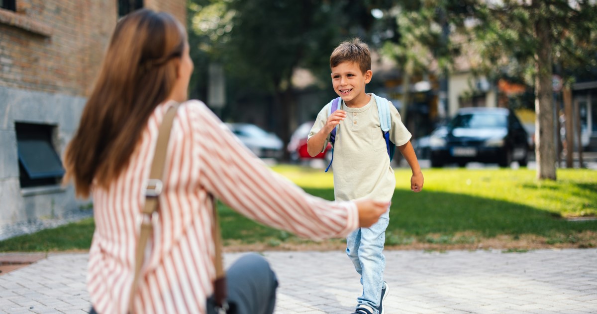 kisfiú megy haza az iskolából, anyukája várja