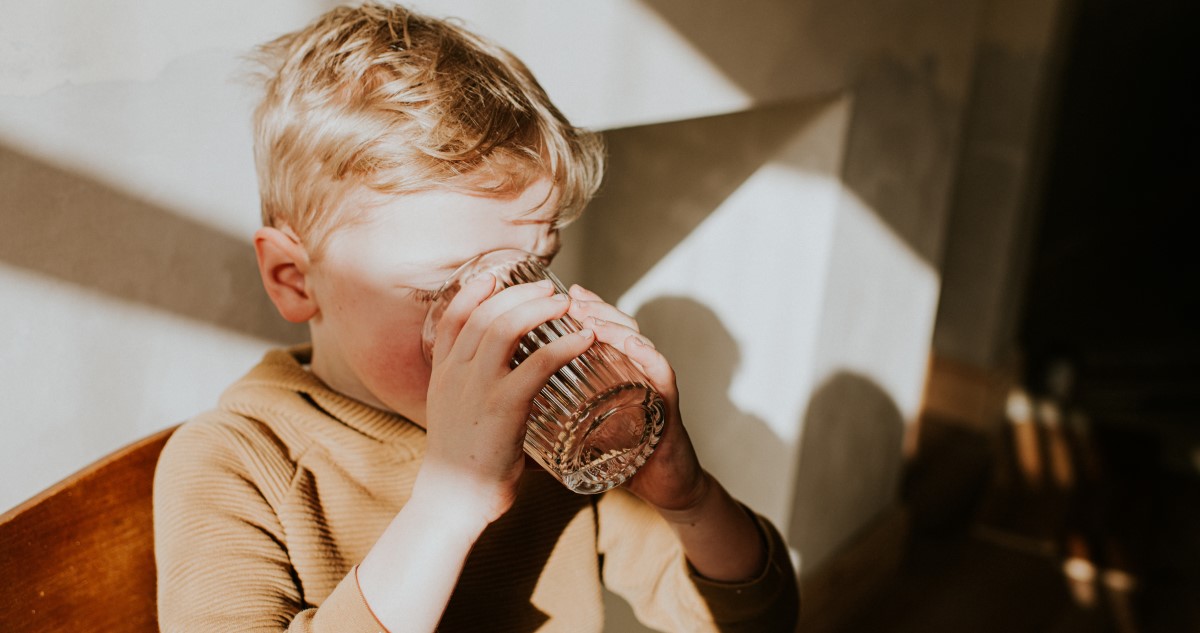 kisfiú konyhaasztalnál ül és vizet iszik