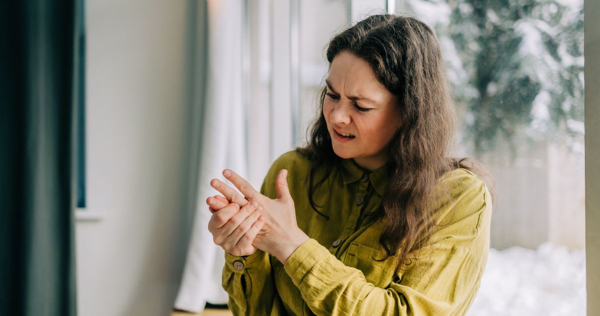Nő erős fájdalmat érez a kezében, és masszírozza őket