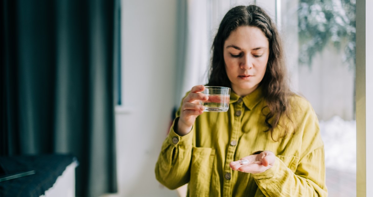 nő olajszínű ingben vitamin vesz b egy pohár vízzel