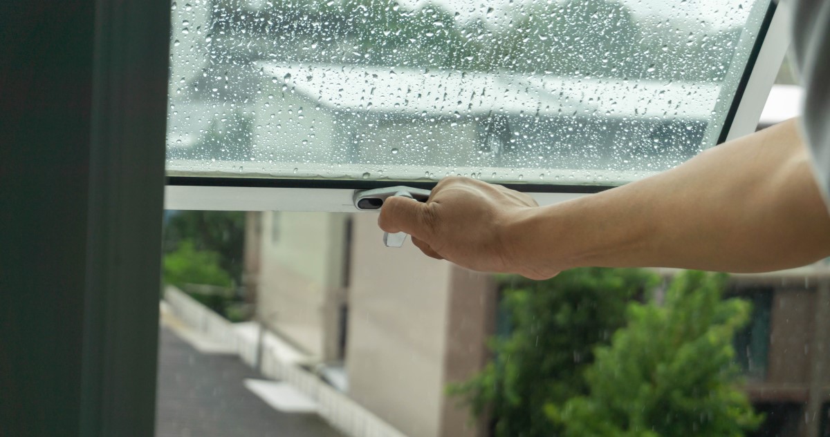 esős időben ablakot nyit egy ember