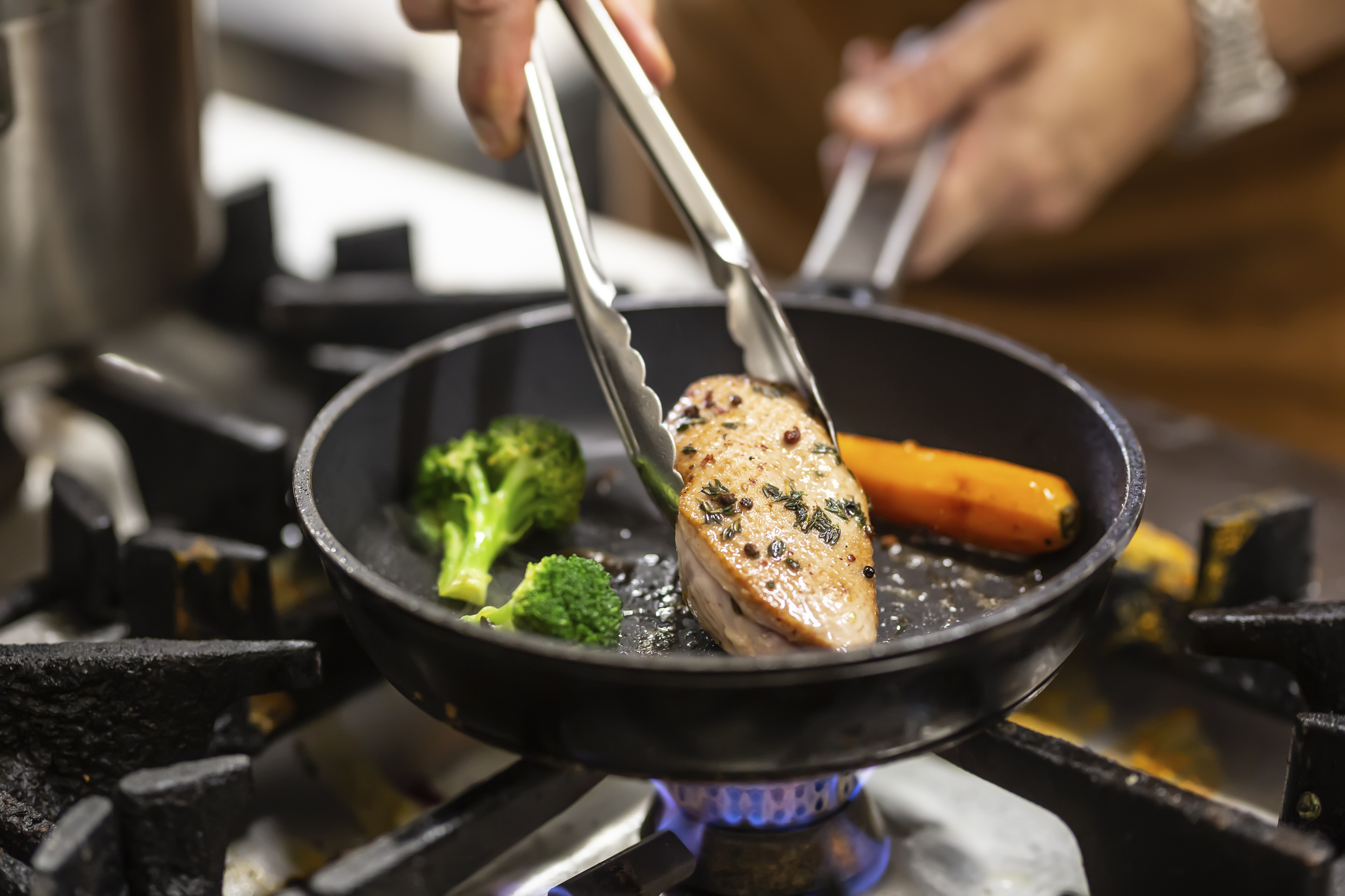 húst és zöldségeket süt serpenyőben