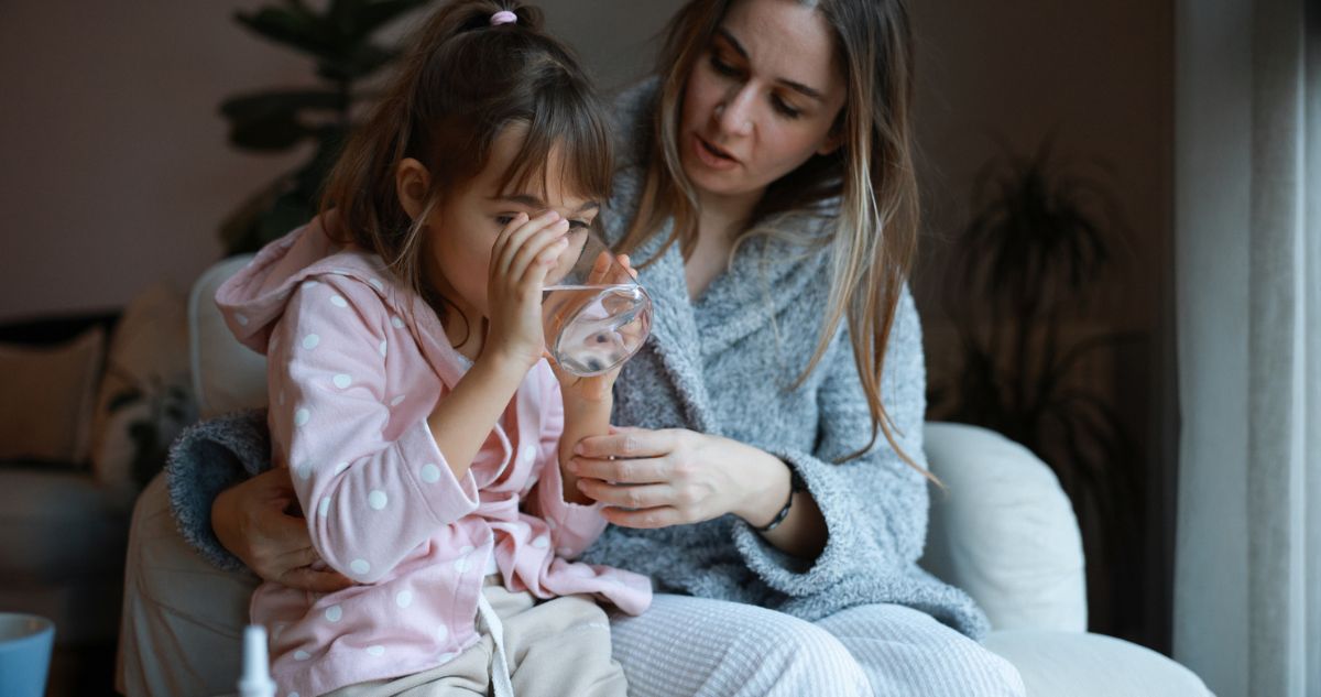 Gondoskodó anya és beteg lánya, aki egy pohár vizet iszik
