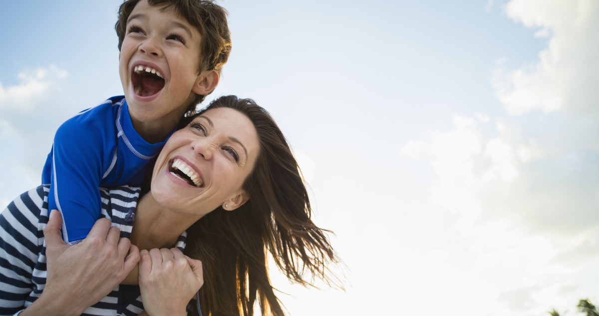 anya hátán a kisfiával nevetnek a szabadban