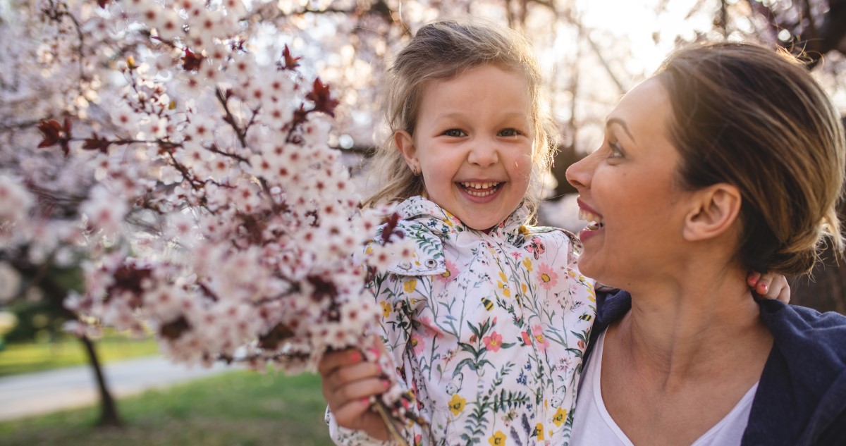 anya lánya tavasszal a parkban virágzó cseresznyefa mellett