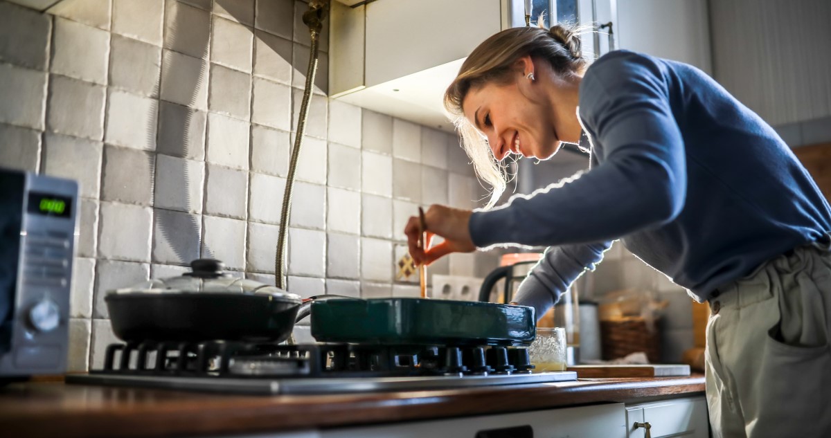 nő főz a konyhában, nagy tűzhelyen