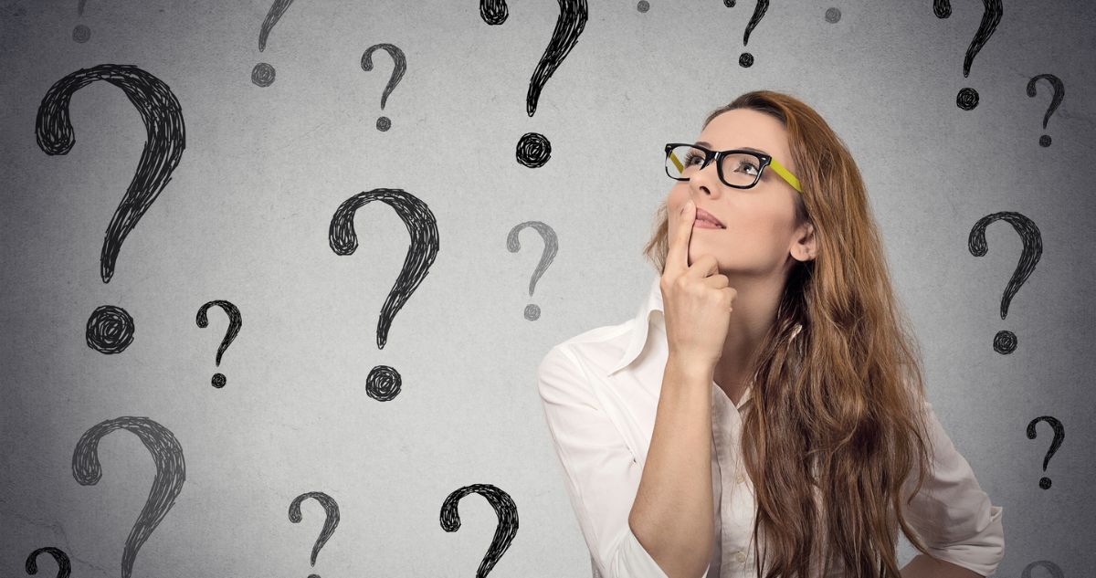 Nő gondolkodik, háttérben kérdőjelek