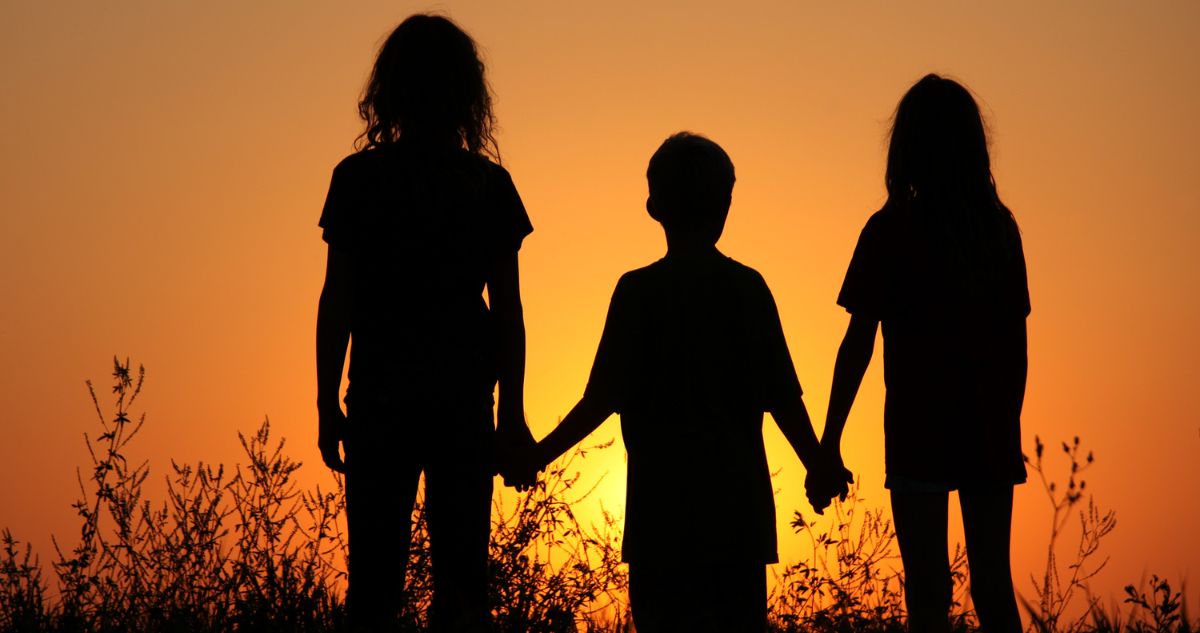 három gyerek sziluettje a naplementében