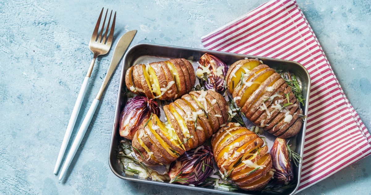 négy Hasselback burgonya tepsiben, hagymával, fokhagymával, zöldfűszerekkel