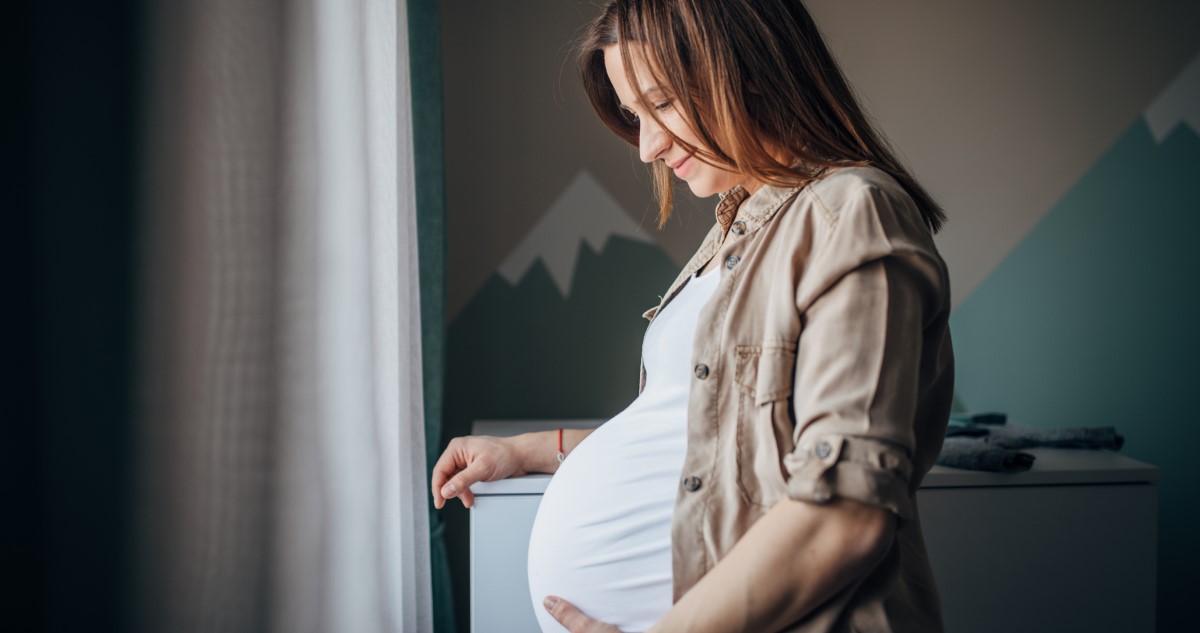 kismama áll a szobában az ablak előtt