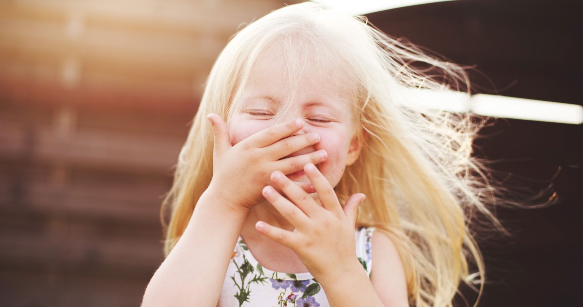 nevető kislány kertben, virágos ruhában