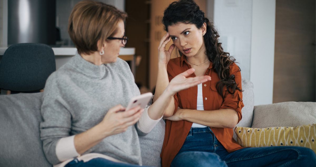 anya és felnőtt lánya a kanapén ülve vitáznak