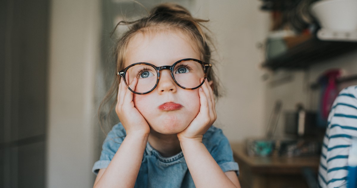 szemüveges kislány könyökére támaszkodik, unatkozó arccal