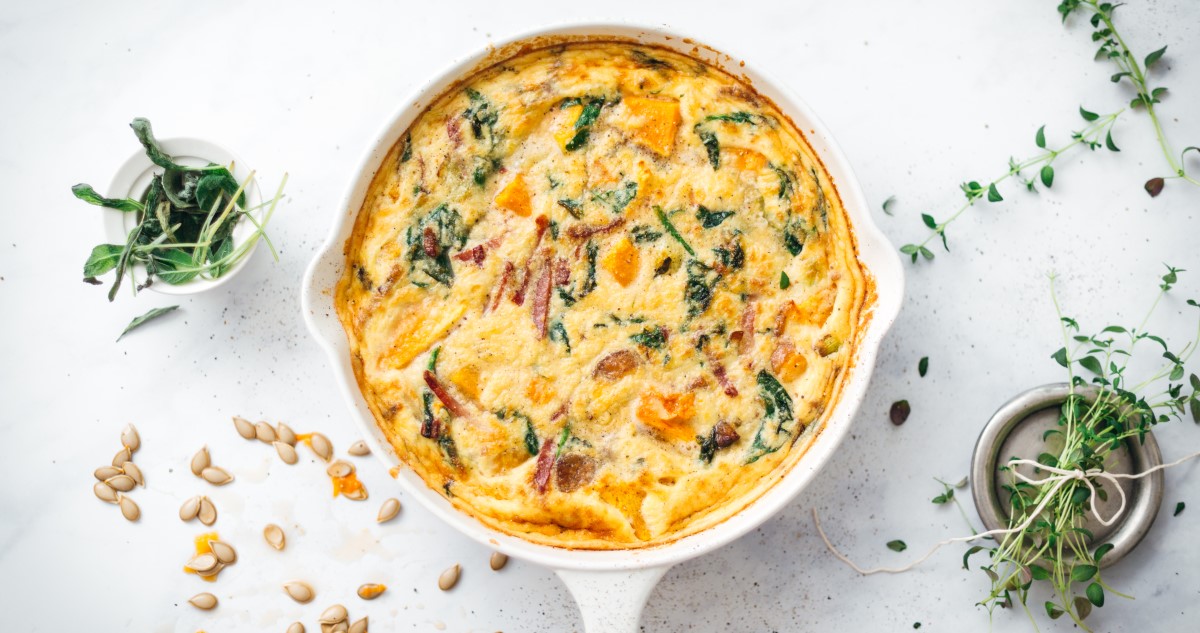 frittata fehér serpenyőben, körülötte magvak és fűszerek