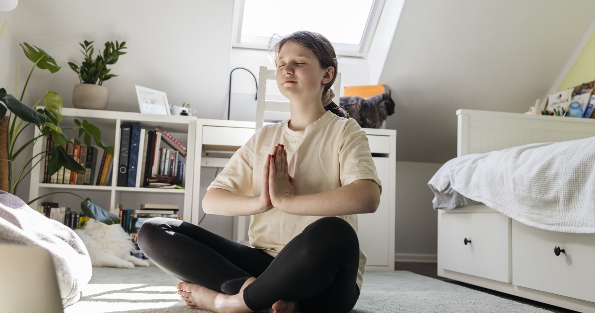 lány meditál a szobájában, a földön ülve