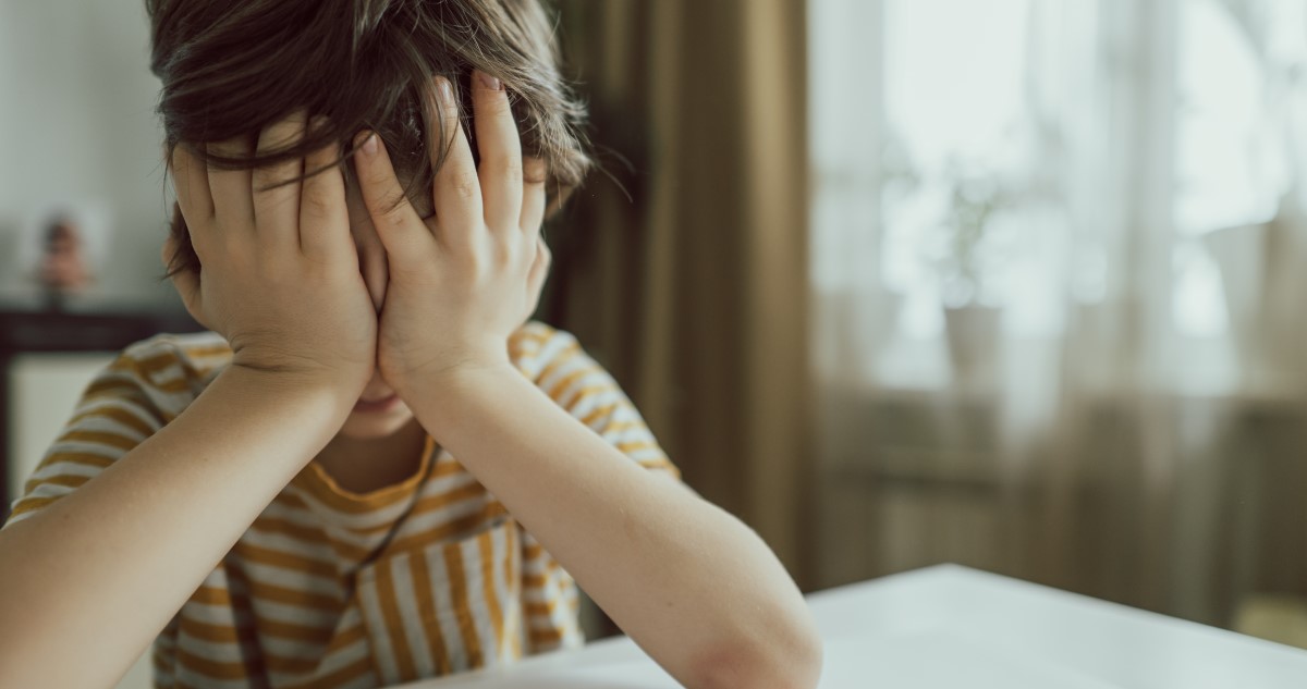 kisfiú szomorúan eltakarja az arcát