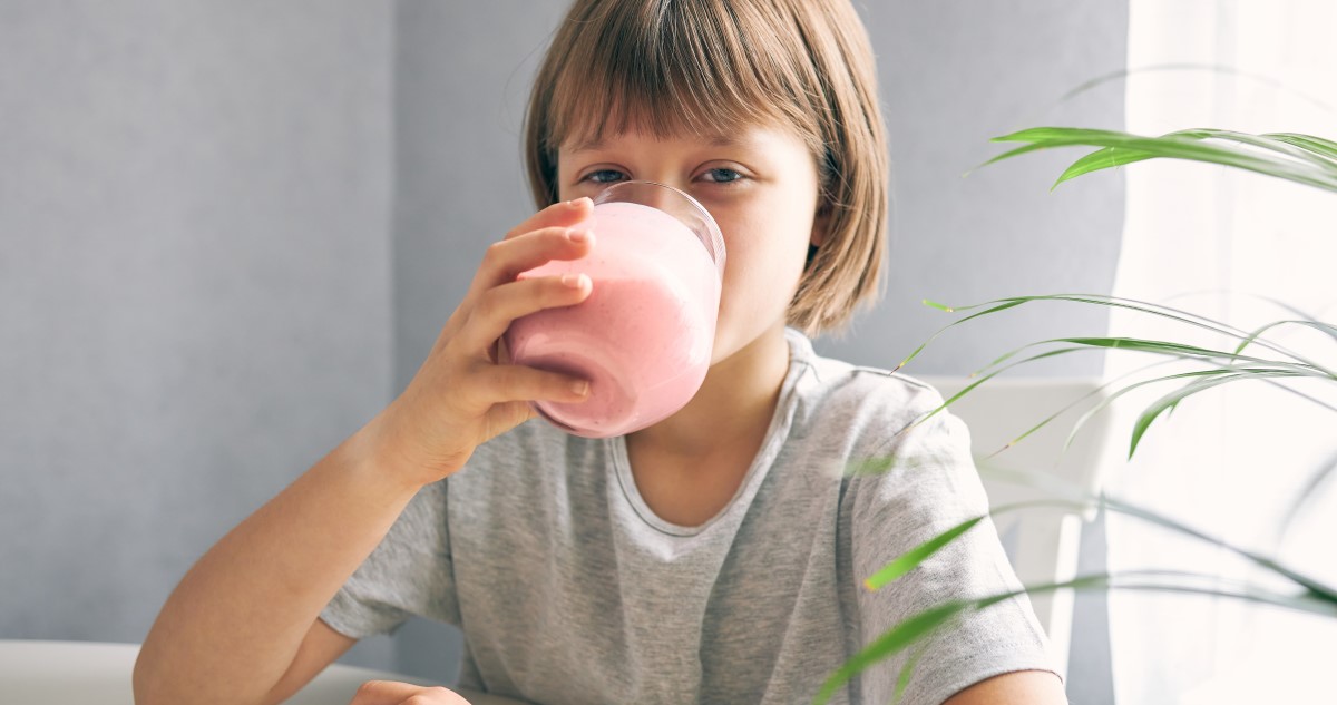 A képen egy iskolás lány látható, aki smoothiet iszik.