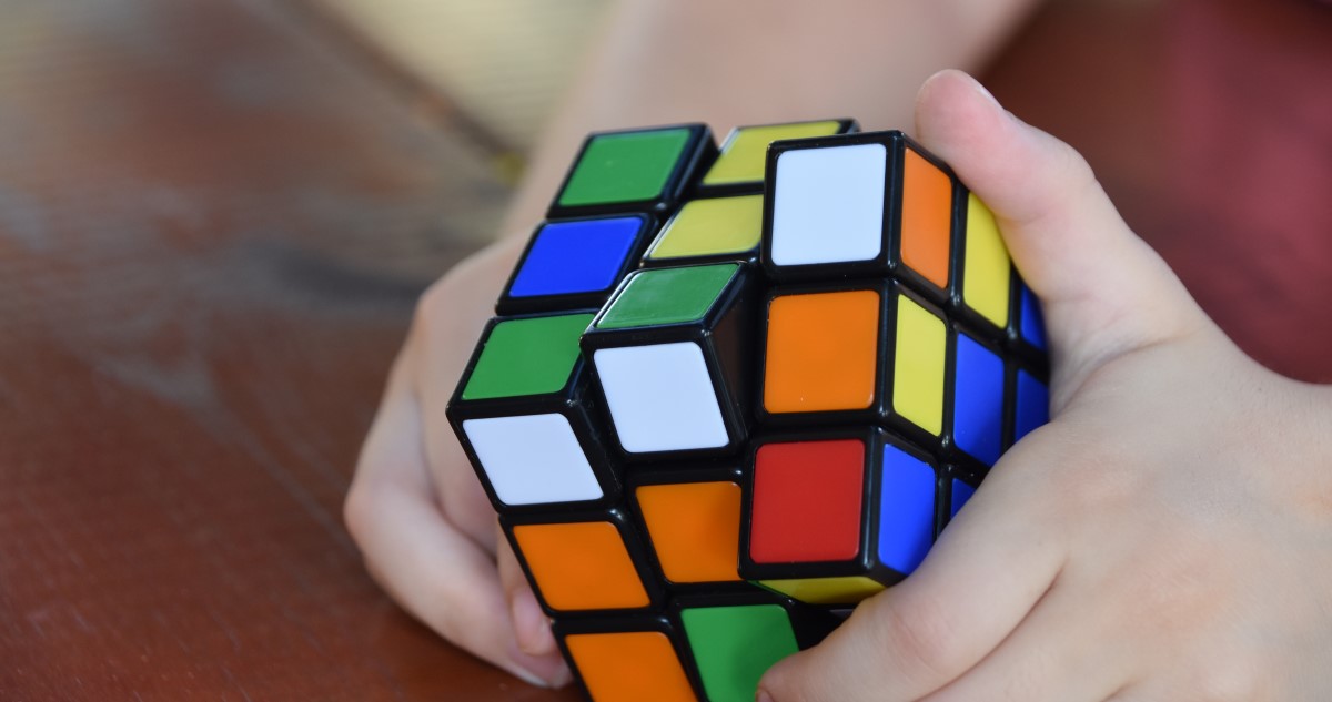 A képen egy gyerek kezében látható közelről egy Rubik-kocka, amit éppen elforgat.