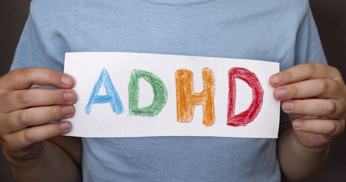 Gyerek színes ADHD feliratot tart a kezében